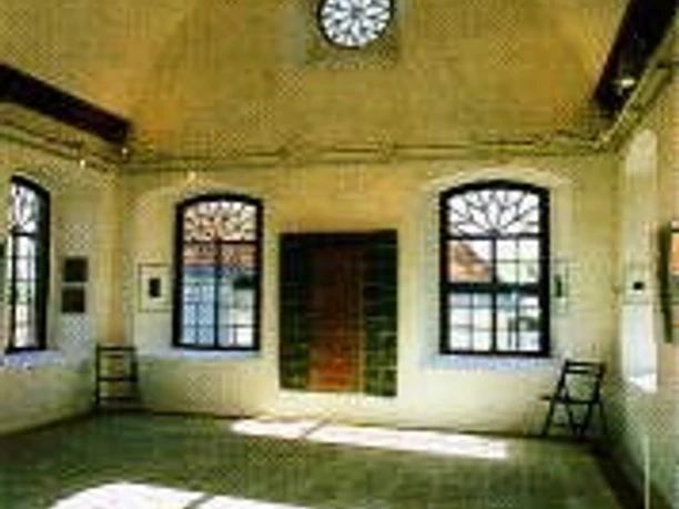 Lichtdurchfluteter Raum mit Holzboden, großen Fenstern, dekorativer Decke und Holztüren.