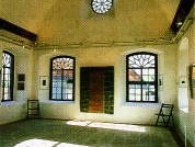 S Lichtdurchfluteter Raum mit Holzboden, großen Fenstern, dekorativer Decke und Holztüren.