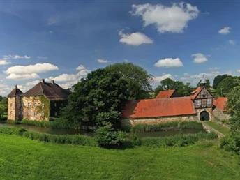 Historisches Herrenhaus von Gut Stockhausen, umgeben von grüner Landschaft und einem Wassergraben.