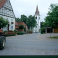 Kirche in Tietelsen Eine gotische Kirche mit spitzem Turm steht am Ende einer ruhigen, von Fachwerkhäusern flankierten Straße.