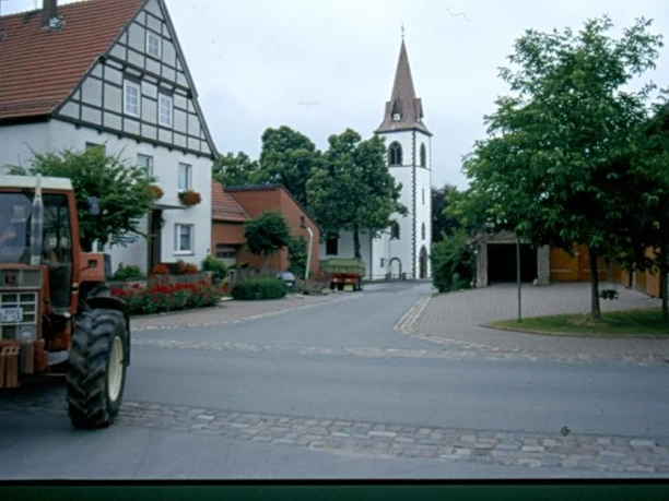 Kirche in Tietelsen Eine gotische Kirche mit spitzem Turm steht am Ende einer ruhigen, von Fachwerkhäusern flankierten Straße.