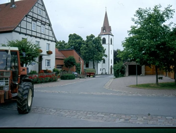 Kirche in Tietelsen Eine gotische Kirche mit spitzem Turm steht am Ende einer ruhigen, von Fachwerkhäusern flankierten Straße.