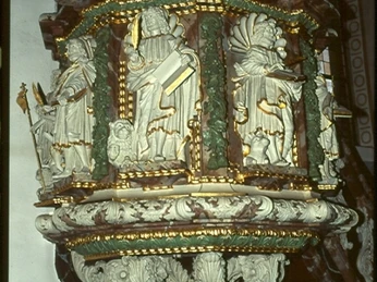 Kanzel Eine reich verzierte Kanzel aus Holz mit goldenen Akzenten, umgeben von Engel- und Heiligenfiguren.