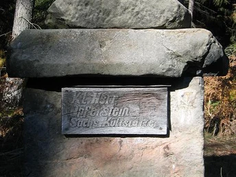 Steinernes Wegekreuz in einem Waldgebiet bei Willebadessen, eingerahmt von hohen Bäumen.