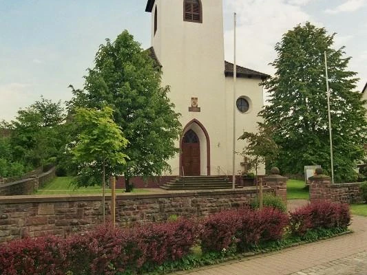 kath. Kirche in Amelunxen Katholische Kirche Amelunxen mit weißem Turm und grünem Dach, flankiert von Bäumen und Büschen.