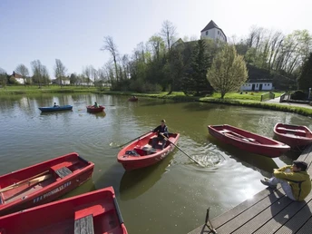 Charlottensee am Bad Iburger Schloss Charlottensee mit Ruderbooten im Vordergrund und Bad Iburger Schloss im Hintergrund bei hellem Wetter.