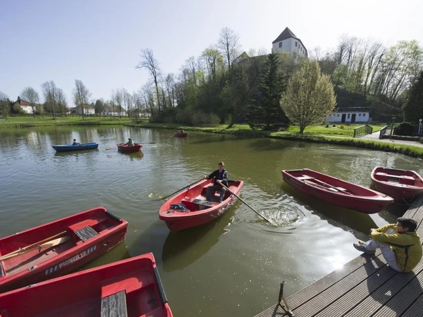 Charlottensee am Bad Iburger Schloss Charlottensee mit Ruderbooten im Vordergrund und Bad Iburger Schloss im Hintergrund bei hellem Wetter.