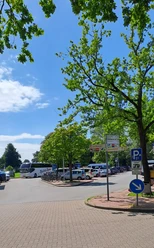 Parkplatz Strandterrassen mit Busparkplatz Parkplatz mit gekennzeichneten Flächen für Busse und Fahrräder, umgeben von grünen Bäumen.