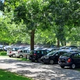 Parkplatz Bruchdamm Parkplatz an einer von Bäumen gesäumten Straße mit vielen parkenden Autos und dichtem Laub im Hintergrund.