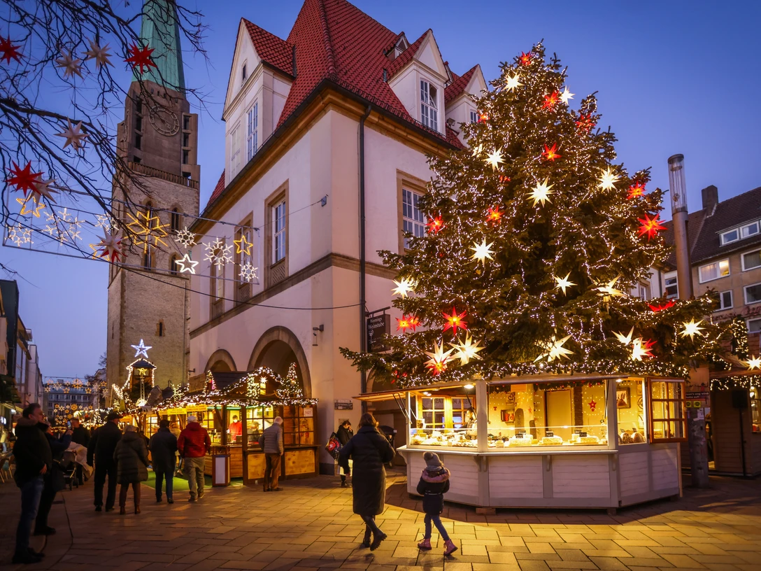 Bielefelder Weihnachtsmarkt Weihnachtsmarkt in der Dämmerung mit festlich beleuchtetem Baum und traditionellen Buden.