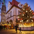 Bielefelder Weihnachtsmarkt Weihnachtsmarkt in der Dämmerung mit festlich beleuchtetem Baum und traditionellen Buden.