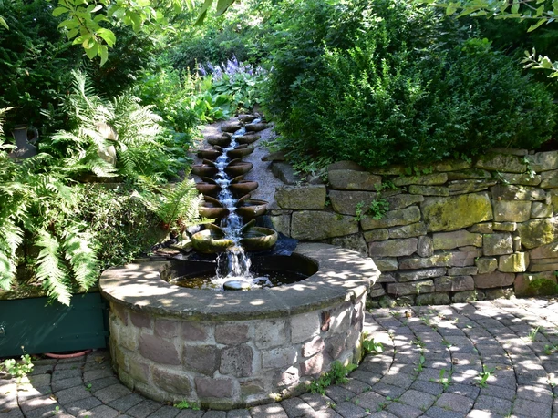 Wasserspiel mündet in einem Brunnen im Lebensgarten Amelunxen