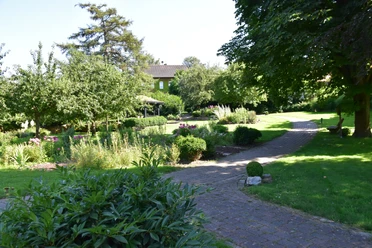 Blick in den Lebensgarten Amelunxen Pflasterweg führt durch den mit Bäumen und Stauden gestalteten Lebensgarten Amelunxen