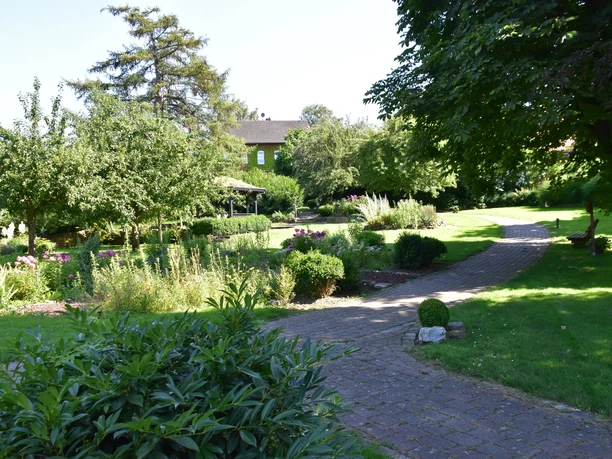 Blick in den Lebensgarten Amelunxen Pflasterweg führt durch den mit Bäumen und Stauden gestalteten Lebensgarten Amelunxen