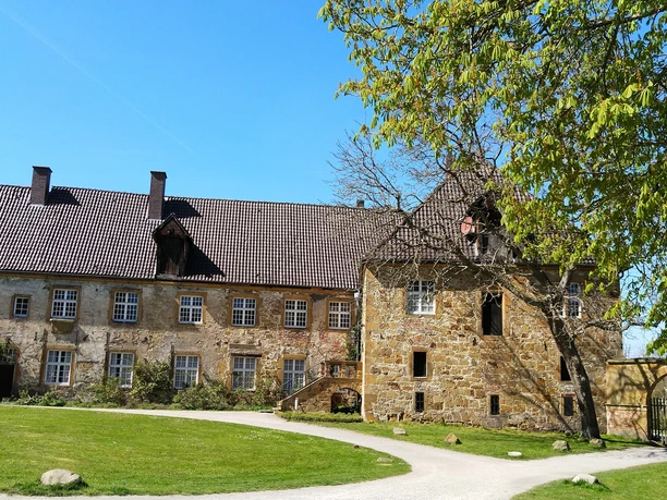 Kloster Herzebrock Historisches Schlossgebäude mit ziegelgedecktem Dach, umgeben von einer gepflegten Rasenfläche.
