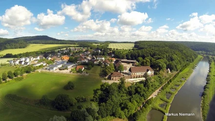 Blankenau im Weserbergland Die Luftaufnahme zeigt den Ort Blankenau. Rechts im Bild fließt die Weser, im Hintergrund sind Felder, Wiesen und Bäume zu sehen.