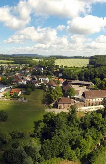 Blankenau im Weserbergland Die Luftaufnahme zeigt den Ort Blankenau. Rechts im Bild fließt die Weser, im Hintergrund sind Felder, Wiesen und Bäume zu sehen.