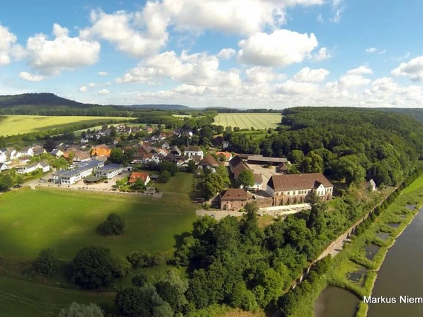 Blankenau im Weserbergland Die Luftaufnahme zeigt den Ort Blankenau. Rechts im Bild fließt die Weser, im Hintergrund sind Felder, Wiesen und Bäume zu sehen.
