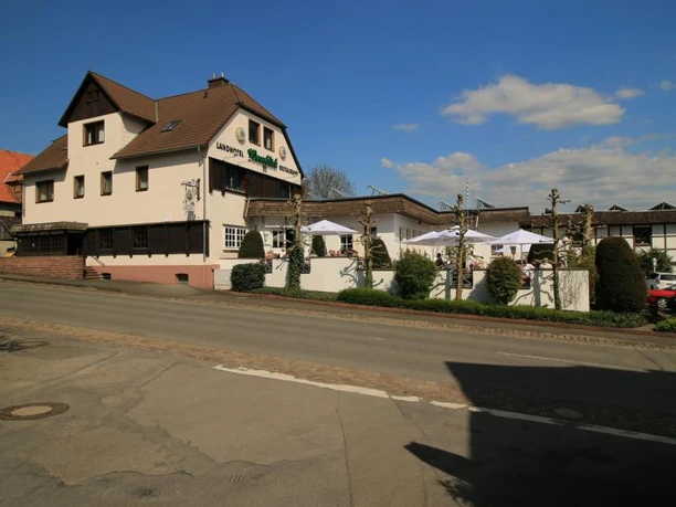 Einkehr in Blankenau Gasthof mit Fachwerkoptik, Außenbereich mit Sonnenschirmen, an einer Landstraße gelegen.