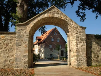 Steinbogen mit Blick auf ein historisches Klostergebäude vor blauem Himmel in Hörstel, Gravenhorst.