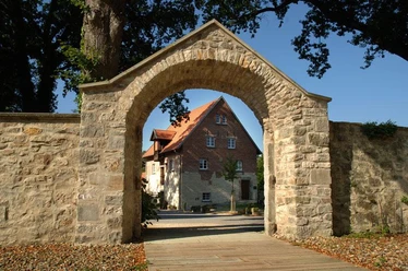 Hörstel - Kloster Gravenhorst Steinbogen mit Blick auf ein historisches Klostergebäude vor blauem Himmel in Hörstel, Gravenhorst.