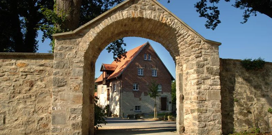 Hörstel - Kloster Gravenhorst Steinbogen mit Blick auf ein historisches Klostergebäude vor blauem Himmel in Hörstel, Gravenhorst.