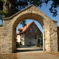 Hörstel - Kloster Gravenhorst Steinbogen mit Blick auf ein historisches Klostergebäude vor blauem Himmel in Hörstel, Gravenhorst.