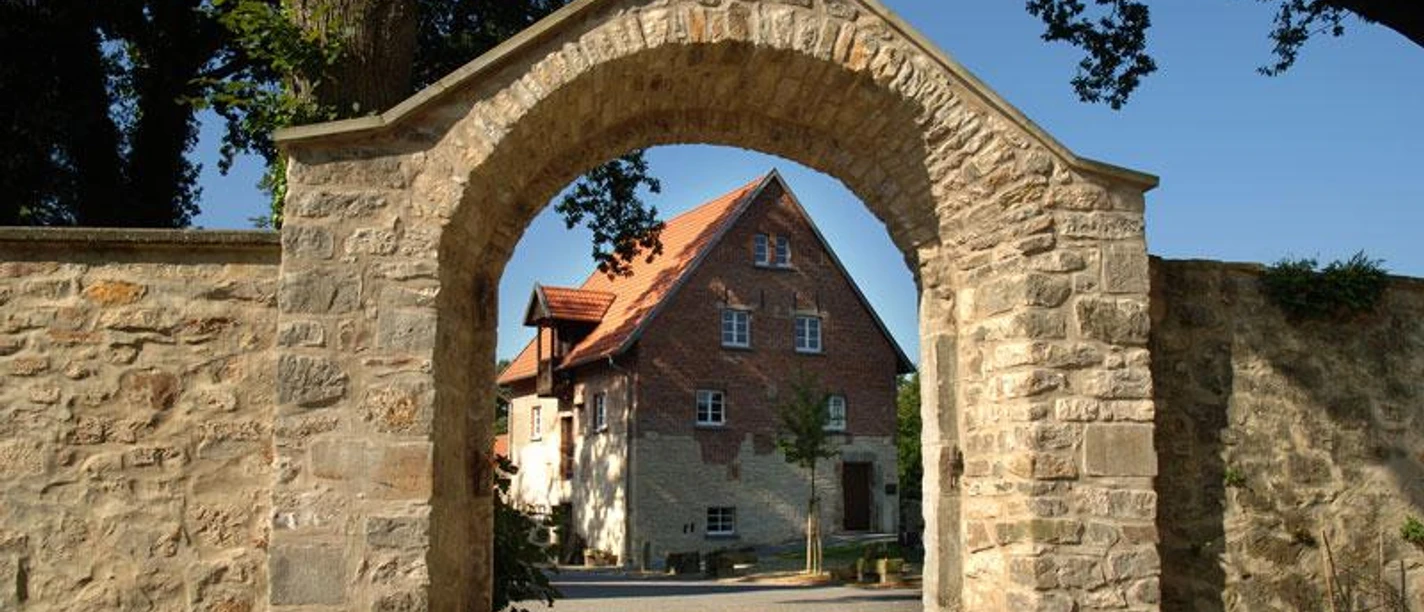 Hörstel - Kloster Gravenhorst Steinbogen mit Blick auf ein historisches Klostergebäude vor blauem Himmel in Hörstel, Gravenhorst.