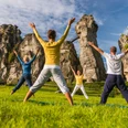 externsteine-horn-bad-meinberg-322-teutoburgerwaldtourismus-dominik-ketz Vier Personen machen Yoga vor den beeindruckenden Felsformationen der Externsteine im Grünen.