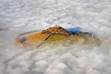 Desenberg im Wolkenmeer Vulkanhügel Desenberg erhebt sich durch Nebel, mit zartem Sonnenlicht auf den Ruinen.