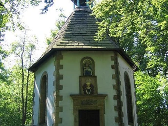 Vituskapelle Willebadessen Achteckige Kapelle im Wald mit Schieferdach und Turm, umgeben von grüner Natur, unten Zugangstür.