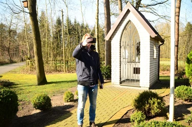Heiligenhäuschen am Wapelweg Ein Mann macht ein Selfie vor einem kleinen, weißen Heiligenhäuschen im sonnigen Wald.