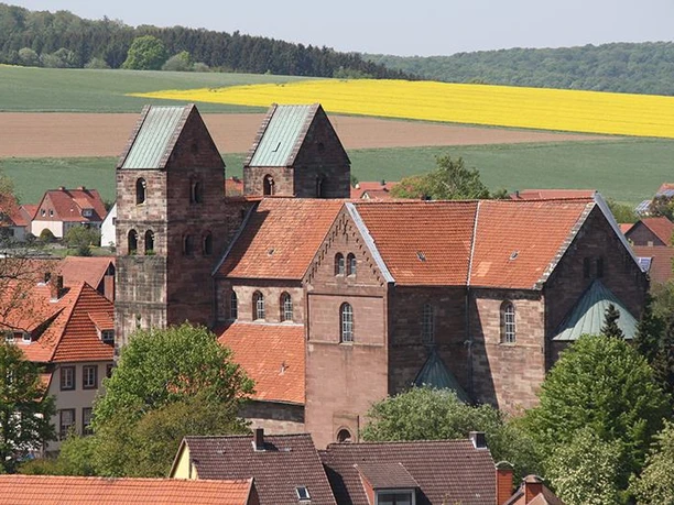 Zwei markante Kirchtürme von Fredelsloh ragen über rote Dächer hinaus, umgeben von grünen Feldern.