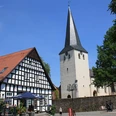 Laurentiuskirche Historische Laurentiuskirche mit markantem spitzen Turm neben einem Fachwerkhaus, blauer Himmel.