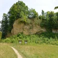 NSG Doberg Waldige Felswand im Naturschutzgebiet Doberg, umgeben von dichter Vegetation und Wiesenpfad.
