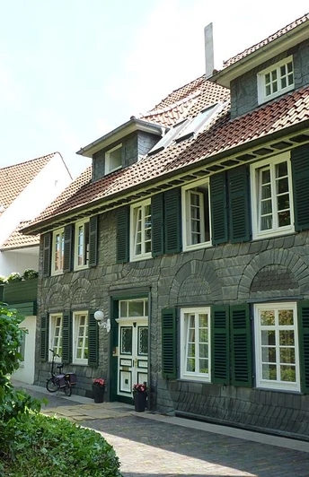 Traditionelles Wohnhaus in Fachwerkstil mit Schieferfassade und grünen Fensterläden.