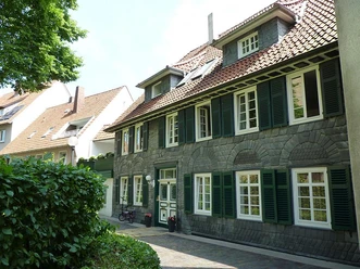 Kirchenrundling Wohnbebauung Traditionelles Wohnhaus in Fachwerkstil mit Schieferfassade und grünen Fensterläden.