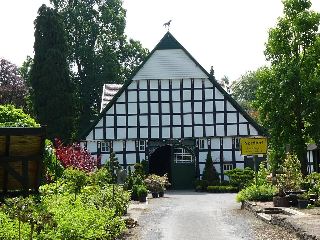 Fachwerkhaus mit markantem Spitzdach, umgeben von üppigem Grün und gepflegten Gartenanlagen.