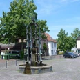 Widukindbrunnen Der Widukindbrunnen steht auf einem gepflasterten Platz, umgeben von Bäumen und historischen Gebäuden.
