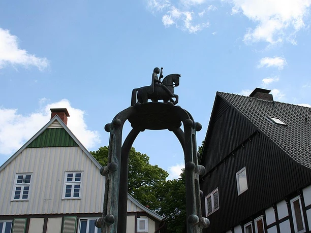 Widukindbrunnen Bronzestatue des historischen Reiters Widukind, auf einem Brunnenbogen vor Fachwerkhäusern gelegen.