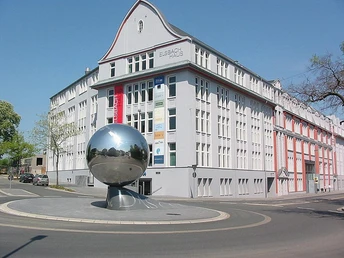 Elsbach Haus mit Kugel-Skulptur Elsbach Haus mit moderner Metallkugel-Skulptur, umgeben von klarer Architektur und blauem Himmel.