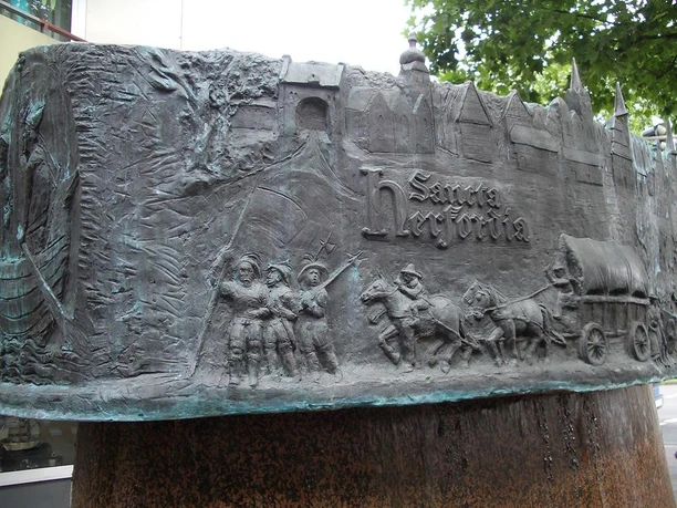 Hansebrunnen Bronzeskulptur des Hansebrunnens in Obernberg am Inn zeigt historische Szenen und Figuren.