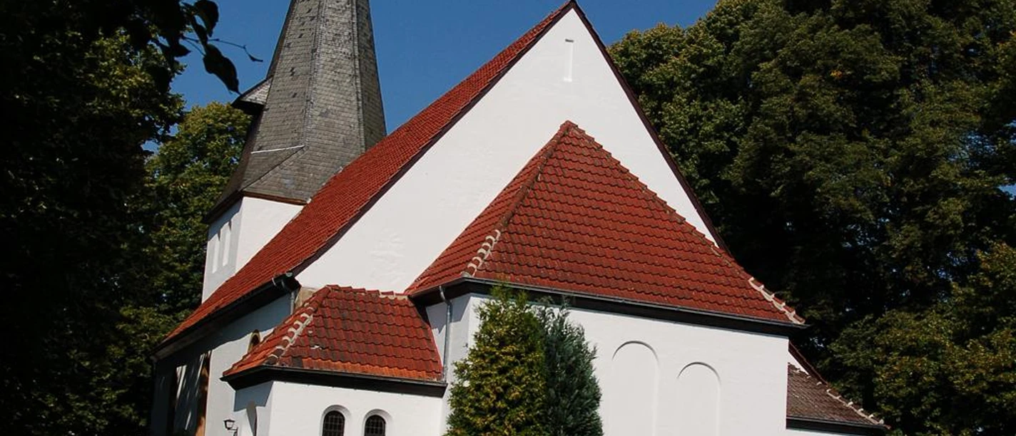 St. Gangolf-Pfarrkirche St. Gangolf-Pfarrkirche im Sonnenlicht, umgeben von Bäumen, mit markantem spitzen Kirchturm.