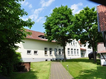 Heimatmuseum Löhne Das Heimatmuseum Löhne, ein weißes Gebäude mit rotem Dach, umgeben von grünen Bäumen und Rasen.