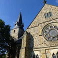 Romanische Kirche St. Bartholomäus mit markantem Glockenturm und beeindruckendem Rundfenster.