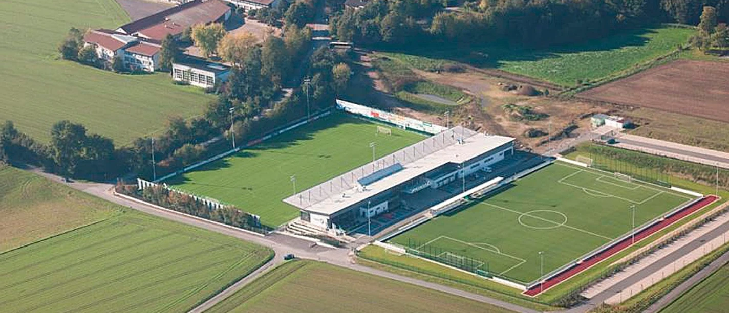 Luftaufnahme des Häcker Wiehenstadions, umgeben von Feldern und Gebäuden in einer ländlichen Umgebung.