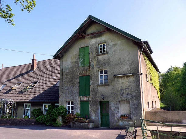 Niedermühle Eine alte Mühle aus dem 19. Jahrhundert mit grünen Fensterläden neben einem modernen Anbau.