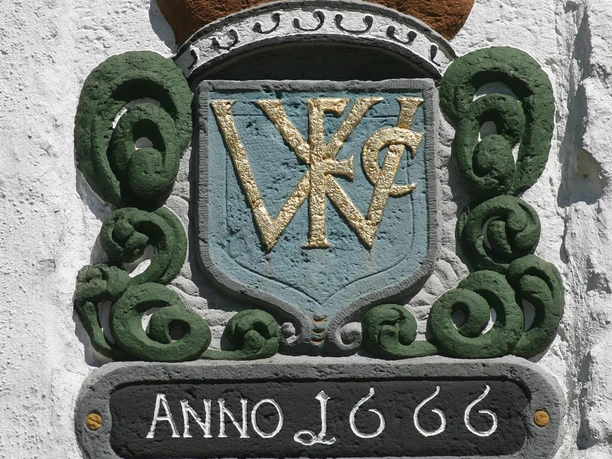 Autobahnkirche Exter Wappenstein mit goldenen Buchstaben "VWC", umgeben von grünen Ornamenten, darunter Jahreszahl 1666.
