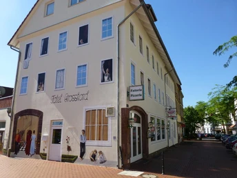 Eine Gebäudefassade mit täuschend echten Wandmalereien von Figuren in Fenstern und Türen.