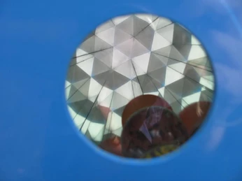 Nach dem Wippen rollen kleine Kugeln im Kaleidoskop auf Sie zu Durch eine blaue Öffnung blickt man auf einen Kristall-Effekt, der an ein Kaleidoskop erinnert.